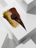 Dark chocolate praline on various chocolate textures with pistachios