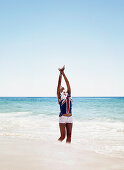 A young woman wearing a top with an Australian flag and shorts on a beach