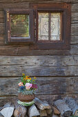 Autumnal flower arrangement in sapucaia nut shell outside rustic wooden house