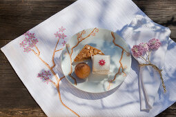 Pastries and petit four on plate on handmade place mat with cherry blossom motif