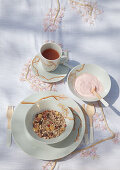 Tea, yoghurt and muesli: crockery and handmade tablecloth with cherry blossom patterns