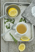 Hot lemon tea with dried lemon leaves on a metal tray