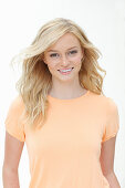 Junge, blonde Frau in apricotfarbenem T-Shirt