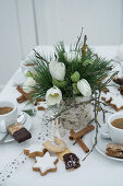 Table set with Christmas biscuits and vase of hellebores for afternoon coffee