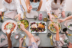Junge Frauen beim Weihnachtsessen mit Truthahn, Salat und Wein
