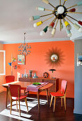 Essbereich vor Sideboard in Retro Ambiente mit orangefarbener Wand