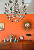 Blick auf Sideboard und Sonnenspiegel an orangefarbener Wand