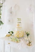 Wedding cake on sideboard and white paper decorations on wall