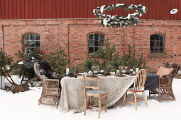 Table set for Christmas below metal wreaths outside brick house