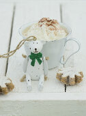 Hot chocolate with cream with a Christmas bear and cinnamon biscuits in front of it