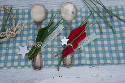 Silver spoons decorated with poinsettia and pine needles used as place cards