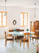 Modern dining table with glass top and Biedermeier furniture in bright dining room