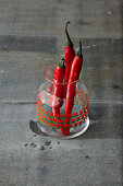 Three fresh red chilli peppers in a glass jar