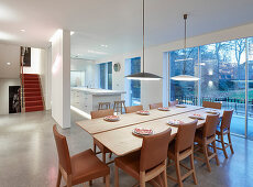 Leather chairs in elegant dining area next to terrace doors; island counter in kitchen in background
