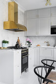 Pale grey fitted kitchen with marble splashback and brass extractor hood