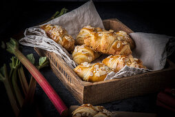 Rhubarb croissants on a linen cloth in a wooden crate (Denmark)