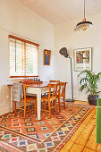 Holztisch mit Schachbrett und Stühlen vor Fenster, Stehlleuchte und Zimmerpflanze im Hintergrund