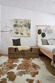 Rat chests with sheepskin next to bed and animal fur rug in bedroom