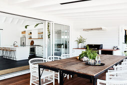 Dining table with rustic wooden top and white rattan chairs