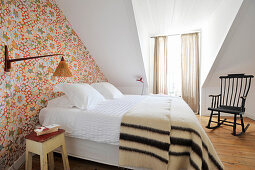 Double bed and patterned wallpaper in attic guest room