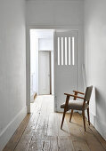 Armchair on wooden floor in simple white corridor