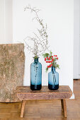 Twigs in two blue vases and on old stool