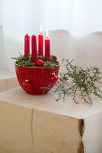 Advent arrangement of four red candles in red mixing bowl