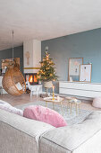 Hängesessel und Weihnachtsbaum am Kamin im Wohnzimmer mit blauer Wand