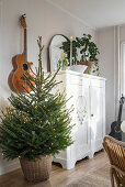 Christmas tree, guitar on wall and white cupboard in living room
