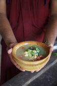 A person holding a small dish of egg soup (India)