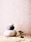 Drei große Steine und Bonsai vor tapezierter Wand