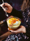 Frau hält Dessertglas mit Orangentrifle