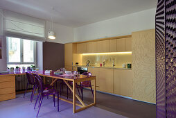 Dining table and purple chairs in front of kitchenette with sliding doors