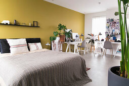 Two desks arranged in an L in bedroom with yellow wall