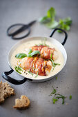 Chicken breast wrapped in bacon in a cream sauce in a pan