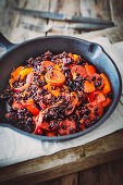 Red pepper and sausage with black rice in a cast iron pan