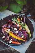 Roasted beets and carrots with goat cheese in a cast iron pan