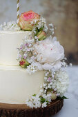 A two-tier wedding cake with butter cream and fresh flowers