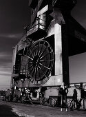 A blonde woman standing in front of an industrial machine (black-and-white shot)