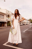 A young woman wearing a long, white dress holding a city map