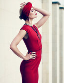 A young woman wearing a red turban headband and a matching cocktail dress