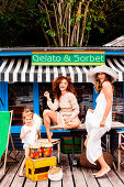 Two women and a little girl wearing light, summer outfits in front of an ice cream parlour