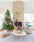 Familie im pastellfarben dekorierten Wohnzimmer mit Weihnachtsbaum
