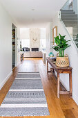 Corridor to the open living room with a long carpet and an old wooden table