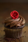 A chocolate cupcake with a cream topping and a marzipan rose