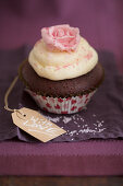 A chocolate cupcake with vanilla cream and a sugar rose