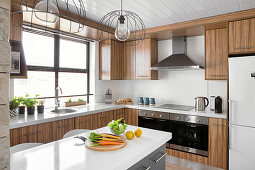 Vegetables on island counter in modern kitchen with wooden cabinets