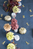 Table set in autumnal style with painted pumpkins and pine cones