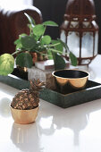 Pineapple ornament in golden bowl in front of Chinese money plant on tray