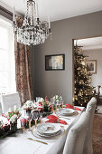 Festively set dining table and Christmas tree visible in open doorway
